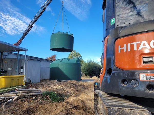 New plastic water tanks being lifted into position on fresh gravel pad