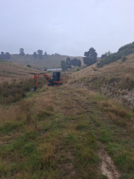DirtPro 5.5 tonne digger cutting drainage features into an owner-built rural track on a Marlborough hillside