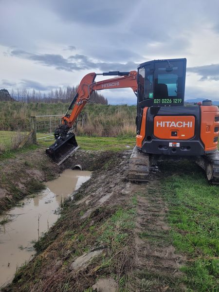 Mini excavator clearing drain swale